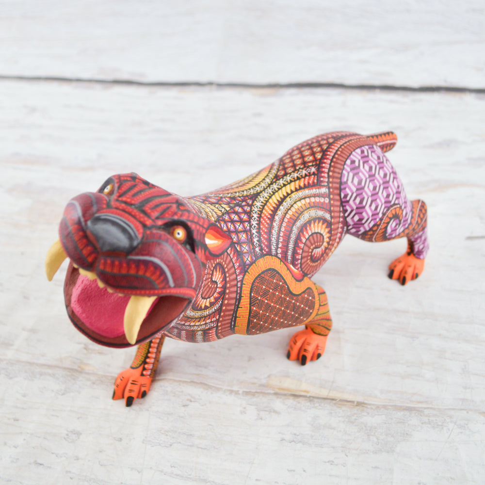 magiamexica.com - Vivid Mexican alebrije shaped like a jaguar, intricately carved and painted with bright colors and detailed patterns, reflecting traditional folk art