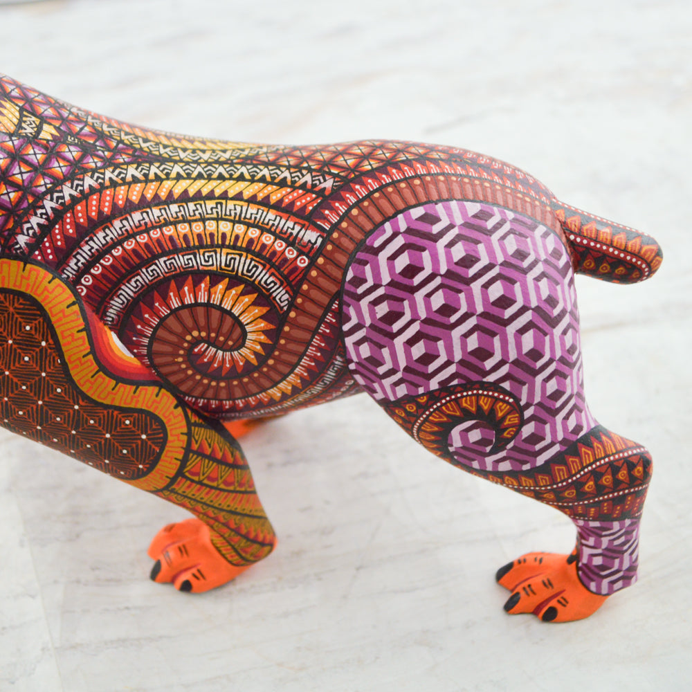 magiamexica.com - Vivid Mexican alebrije shaped like a jaguar, intricately carved and painted with bright colors and detailed patterns, reflecting traditional folk art