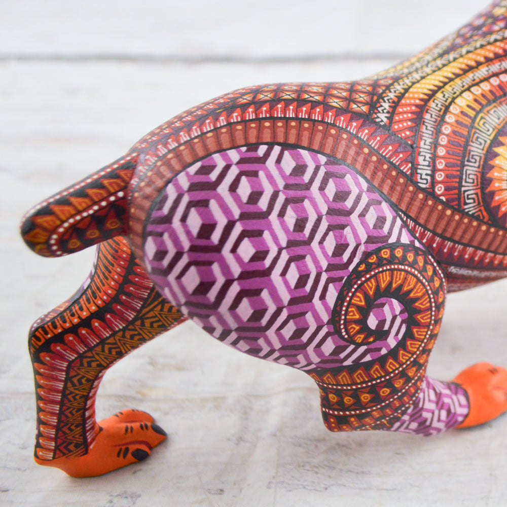 magiamexica.com - Vivid Mexican alebrije shaped like a jaguar, intricately carved and painted with bright colors and detailed patterns, reflecting traditional folk art